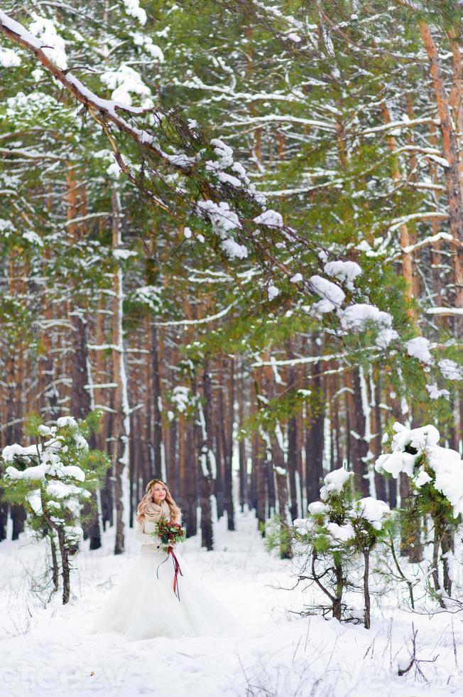 Bride and groom are sitting on the log in the winter forest. Close-up. Winter wedding ceremony. photo