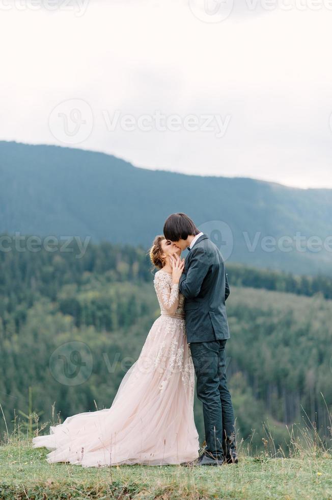 Stylish young bride and groom stand in boat on background cloude sky sea and mountains of Montenegro photo