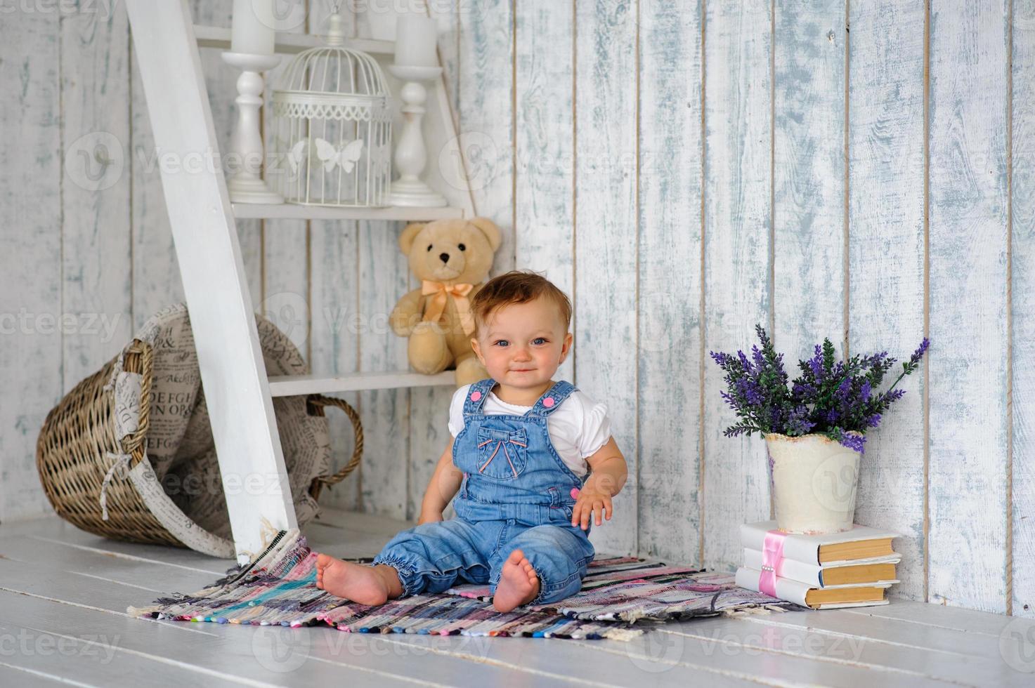 The little one-year-old girl smiles and sits. photo