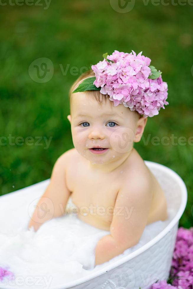 Little girl bathes in a milk bath in the park. The girl is having fun in the summer. photo