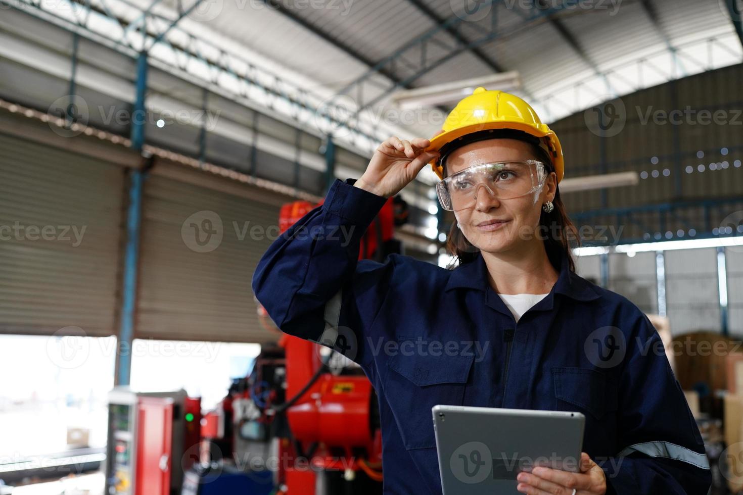 Professional young industrial factory woman employee working with machine part, checking and testing industrial equipment and robot arms in large Electric electronics wire and manufacturing plant photo