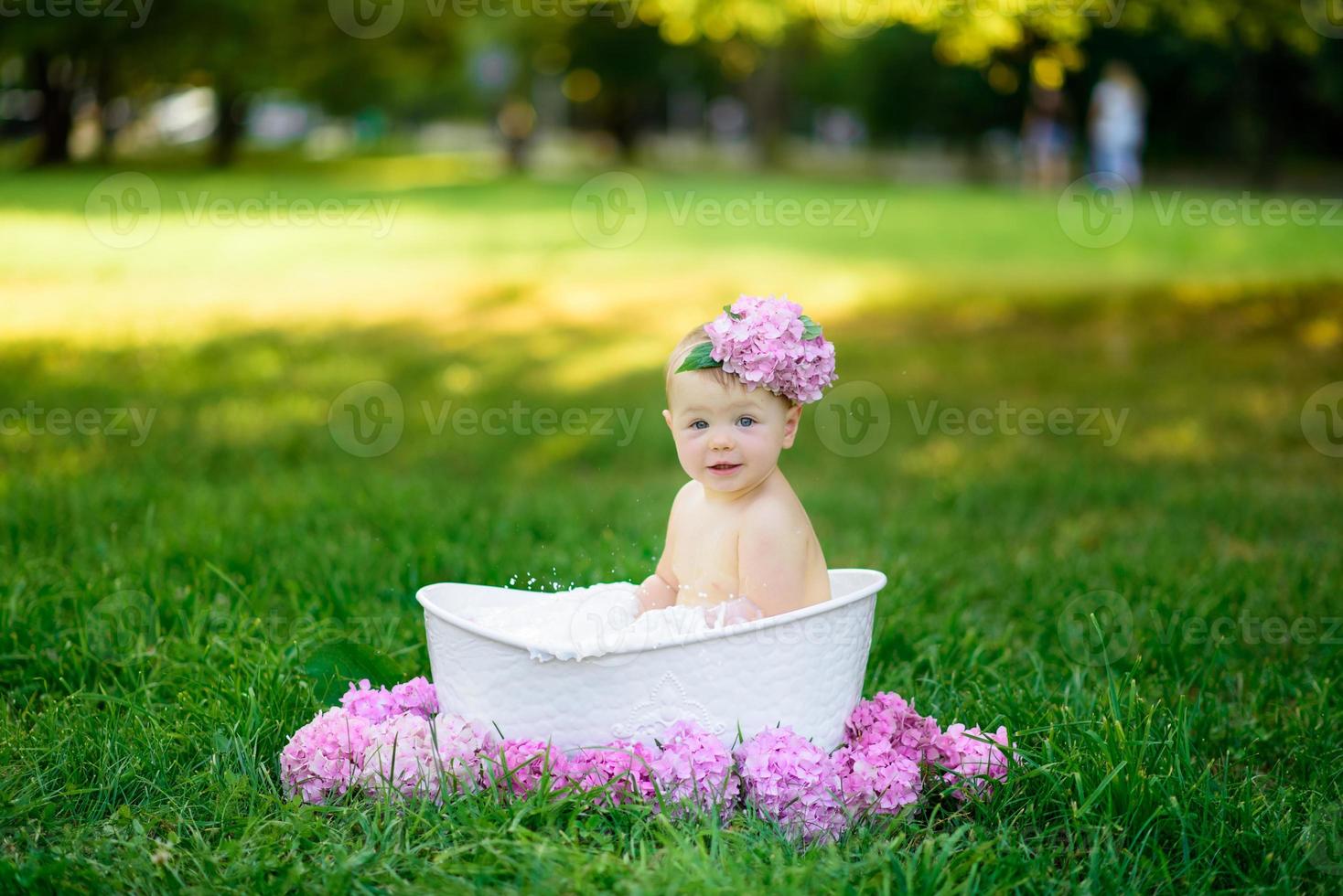 niña se baña en un baño de leche en el parque. la niña se está divirtiendo en el verano. foto