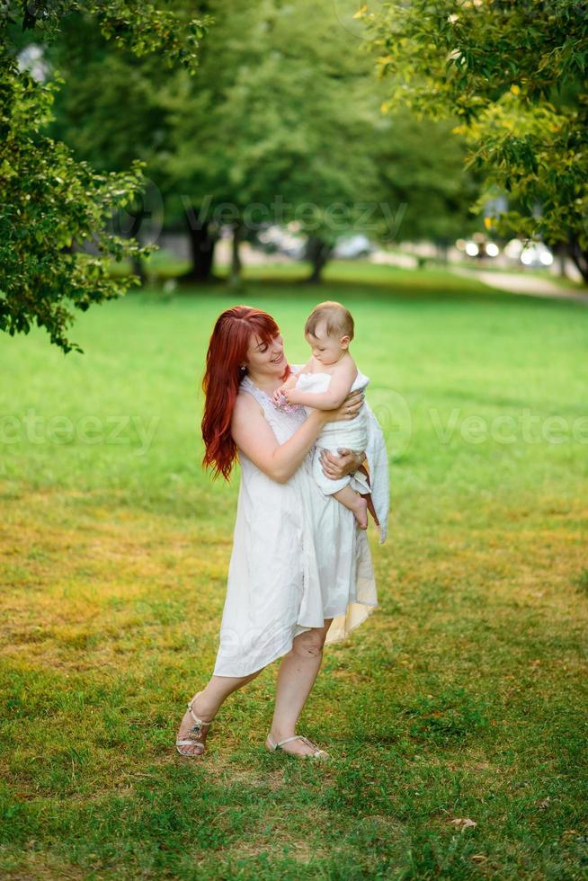 mamá abraza y juega con su hija de un año envuelta en una toalla después del baño. foto