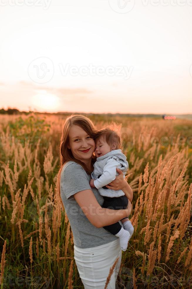 A mother walks in the field with her little daughter in her arms. photo