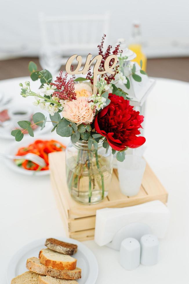 Round dinner tables covered with blue cloth stand in a white wedding pavilion photo