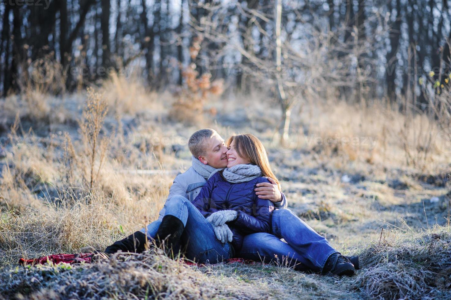 joven y bonita pareja sensual de moda enamorada sentada en un campo frío de invierno foto