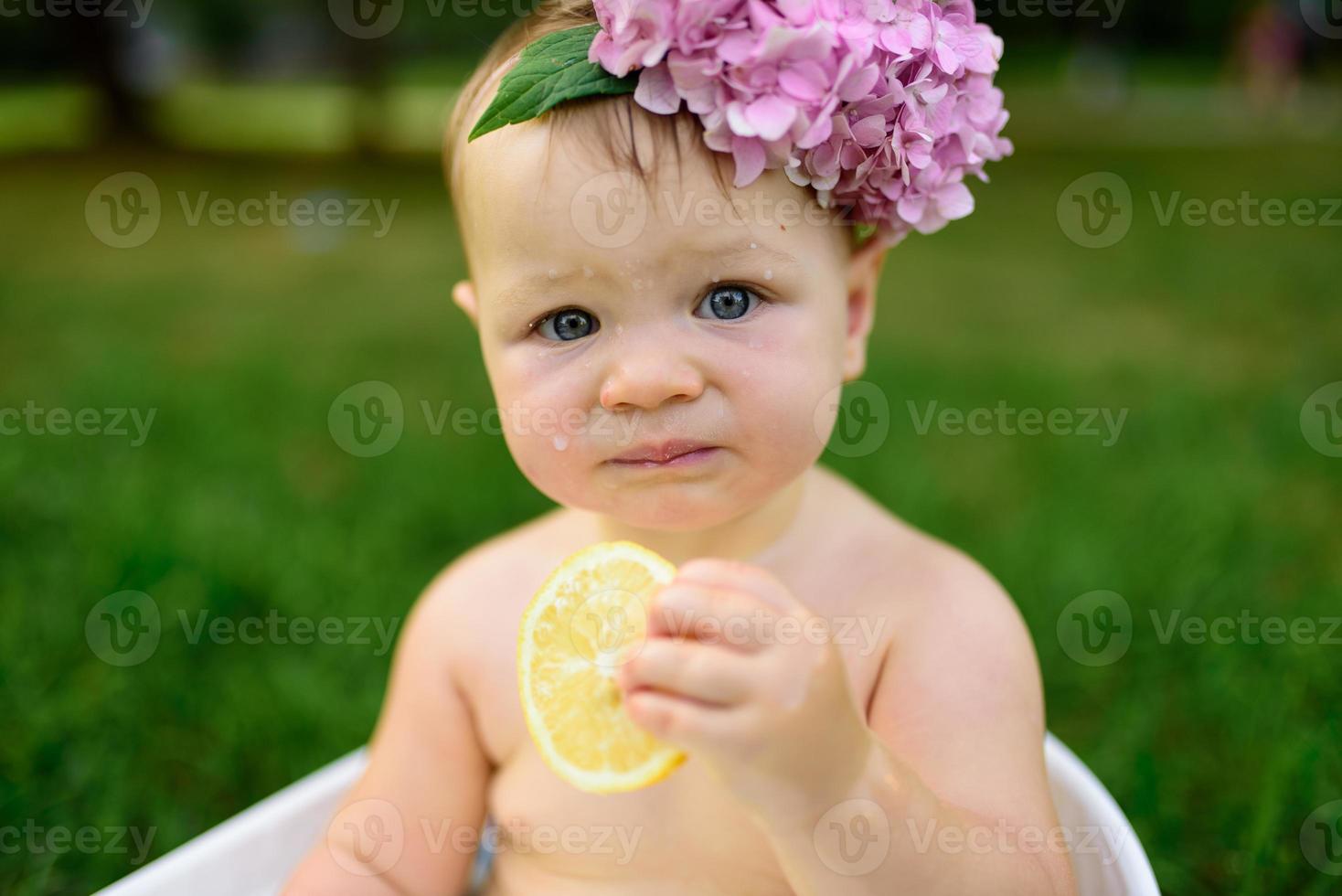 Little girl bathes in a milk bath in the park. The girl is having fun in the summer. photo