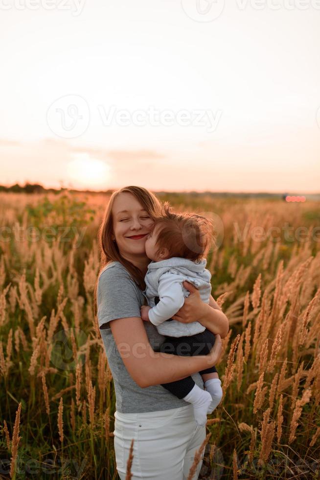 A mother walks in the field with her little daughter in her arms. photo