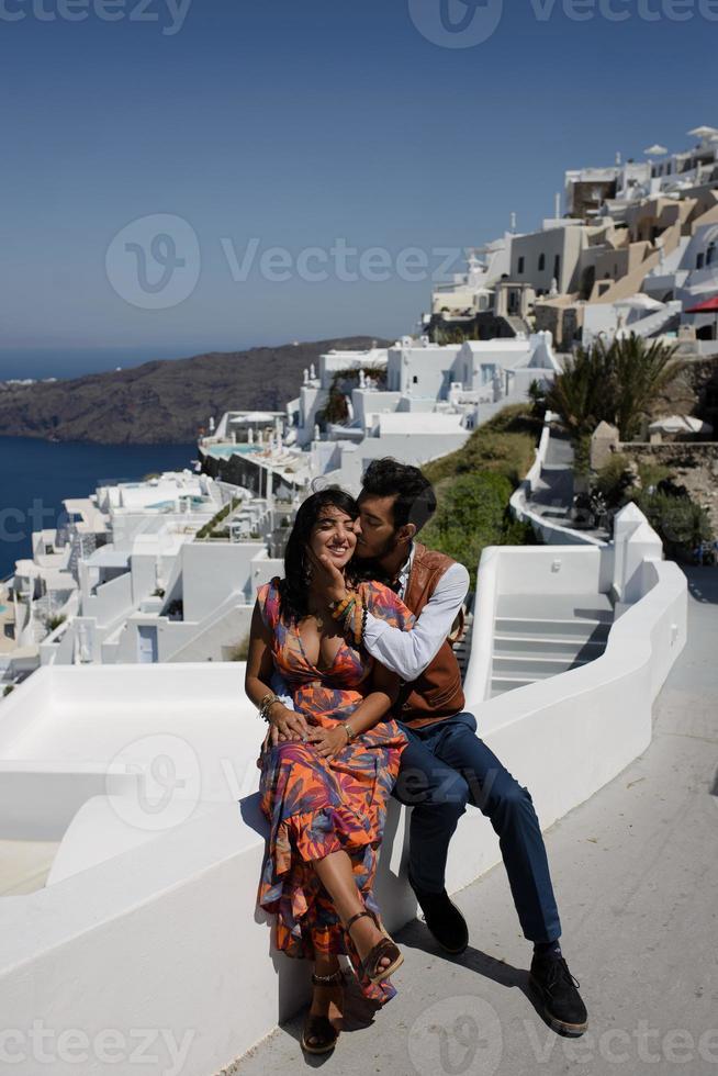 la pareja está sentada en el techo en santorini, abrazándose y riéndose foto