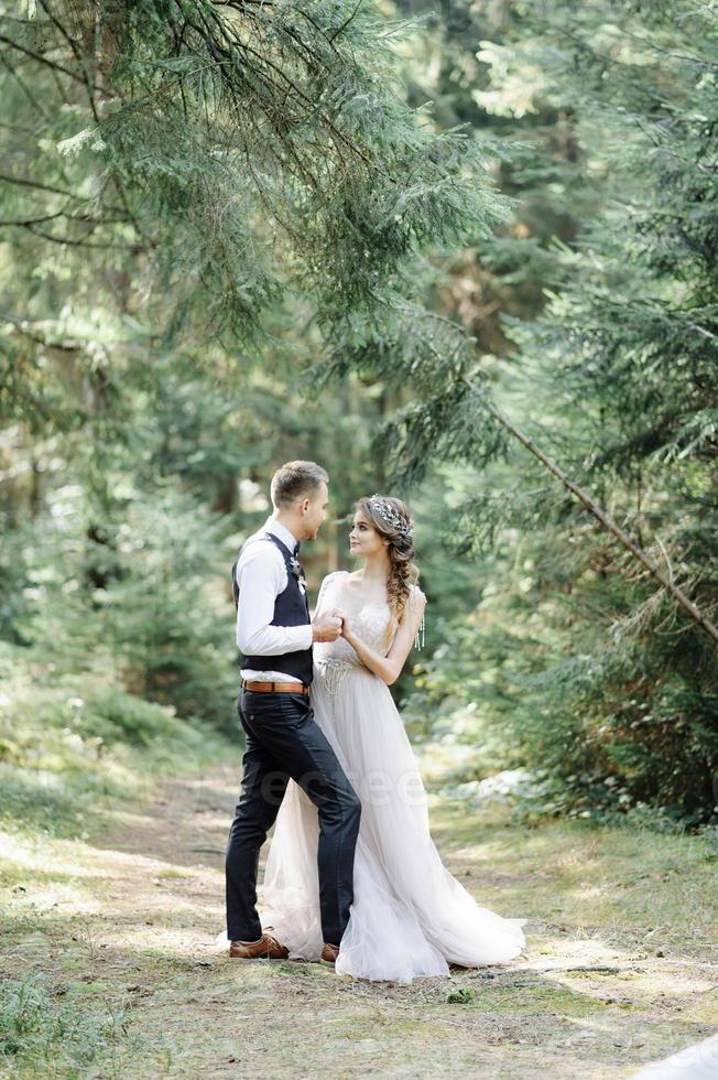 Attractive couple newlyweds, happy and joyful moment. Man and woman in festive clothes sit on the stones near the wedding decoration in boho style. Ceremony outdoors. photo