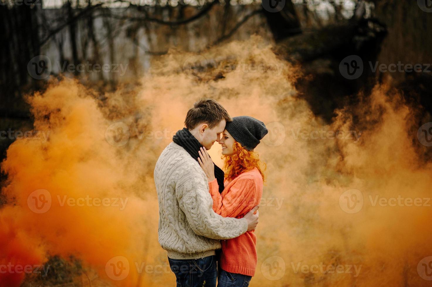 joven pareja feliz sosteniendo bombas de humo en el camping foto