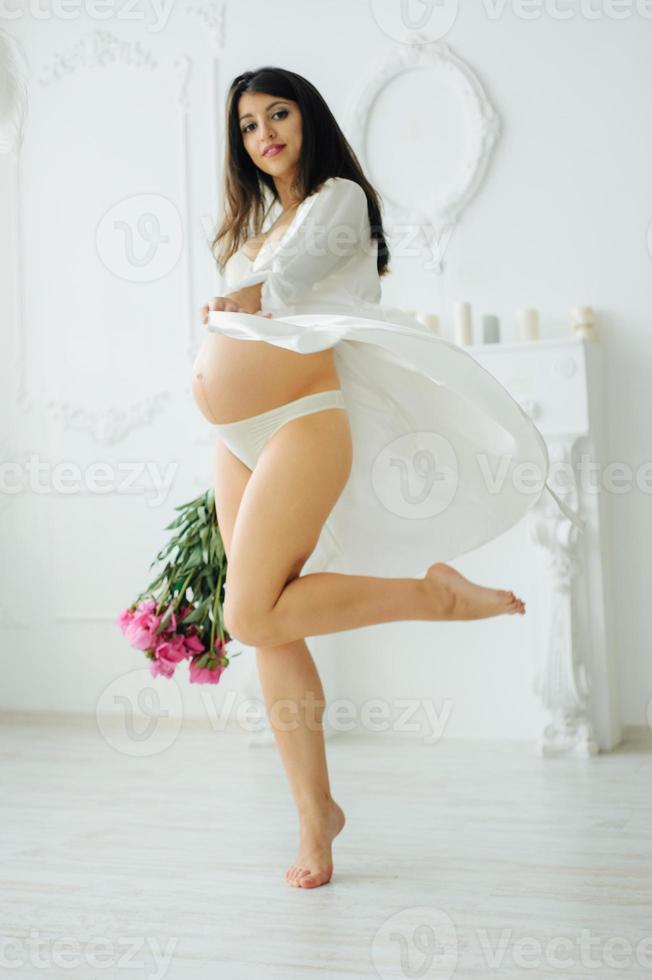 Belly of a pregnant woman. Beautiful pregnant girl. Cropped image of beautiful pregnant woman. Girl in blue shirt and underwear.Touching the pregnant belly.Symbol of the heart with hands photo
