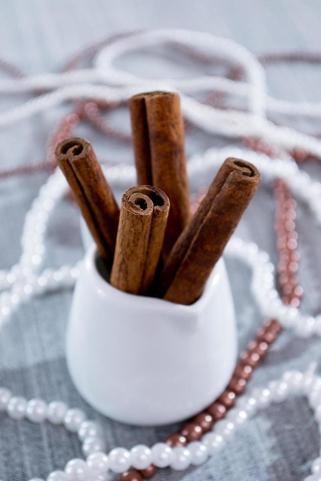 Cinnamon sticks in a glass of white on a blue background photo