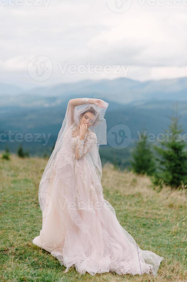 whirling bride holding veil skirt of wedding dress at pine forest photo