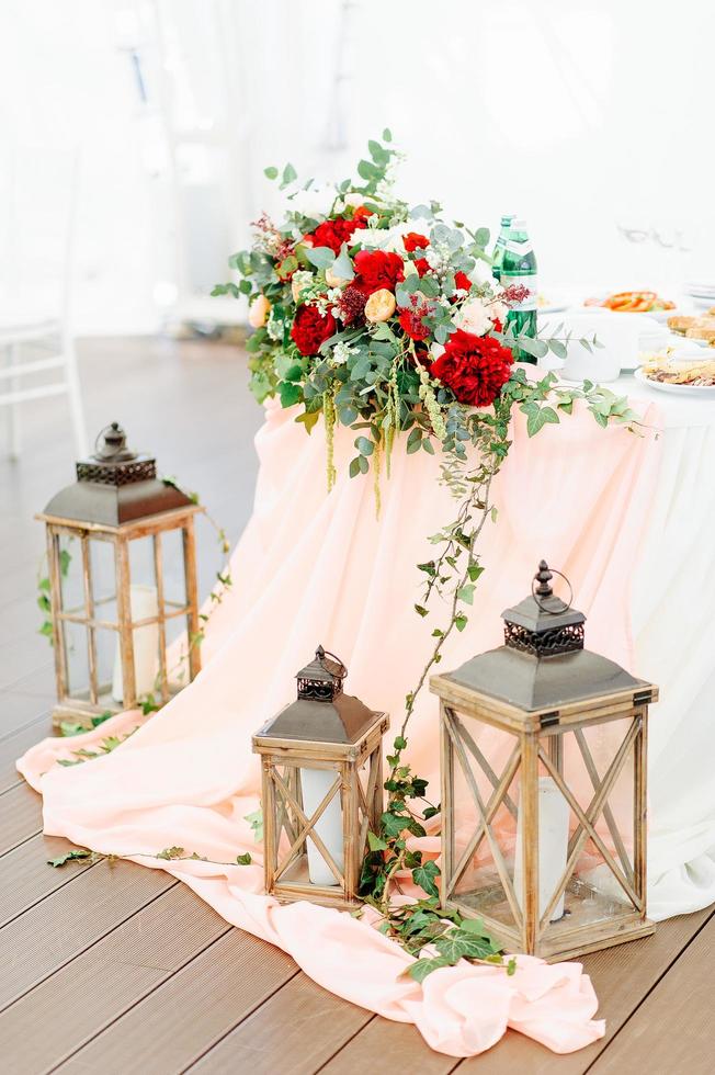 Round dinner tables covered with blue cloth stand in a white wedding pavilion photo