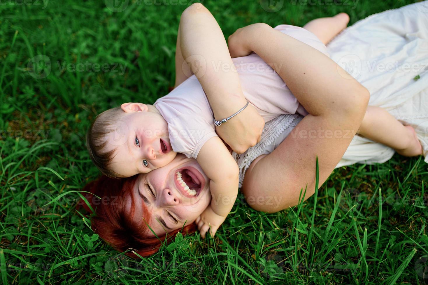 Mom hugs and plays with her one-year-old daughter wrapped in a towel after bathing. photo