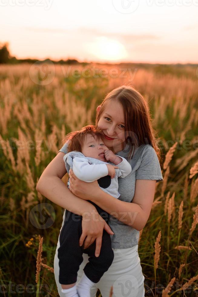 A mother walks in the field with her little daughter in her arms. photo