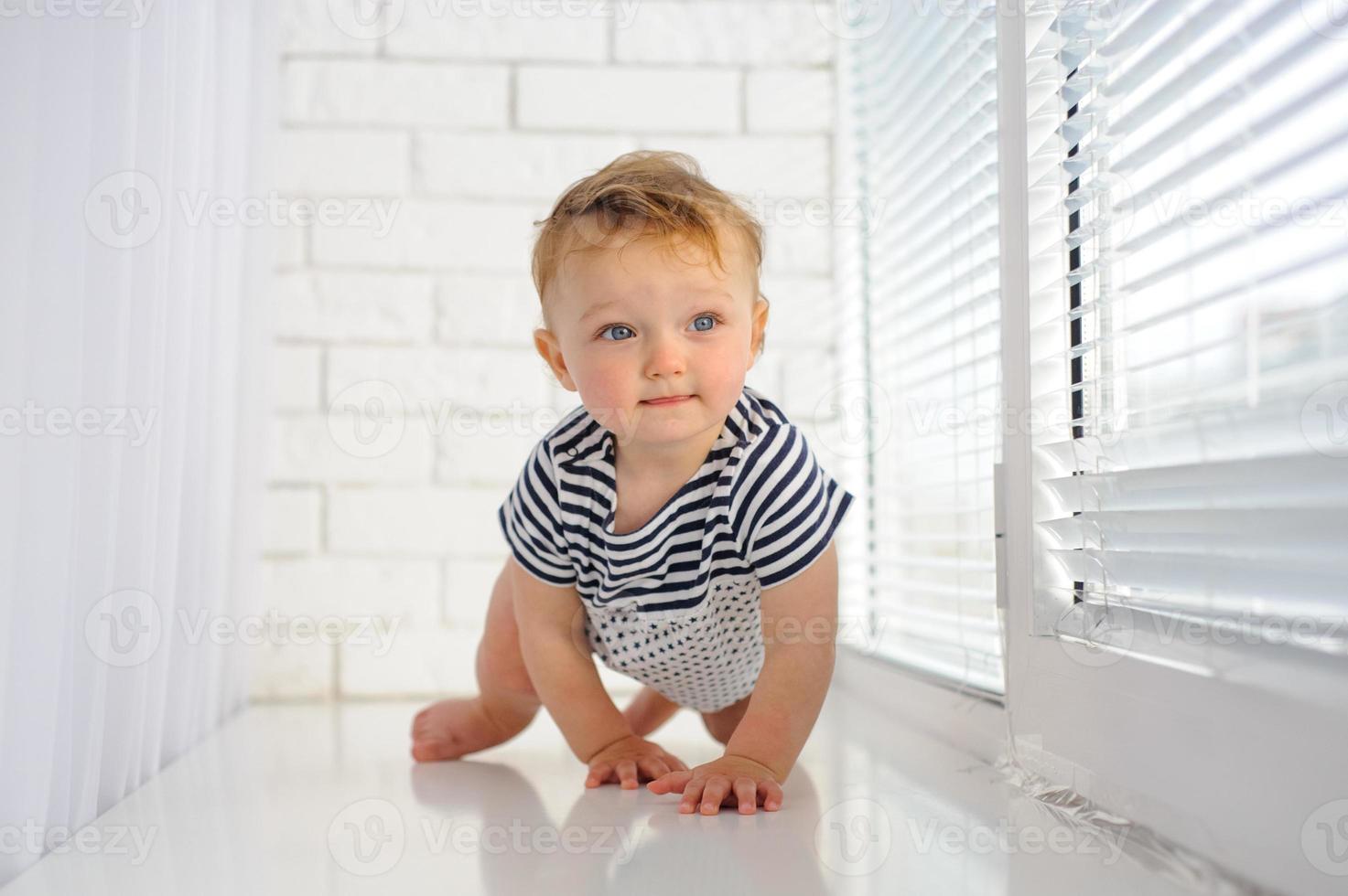 The little one-year-old girl smiles and sits. photo