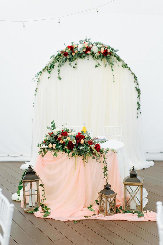 Round dinner tables covered with blue cloth stand in a white wedding pavilion photo