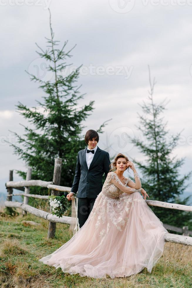 hermosa pareja de bodas besándose y abrazándose cerca de la orilla de un río de montaña con piedras foto