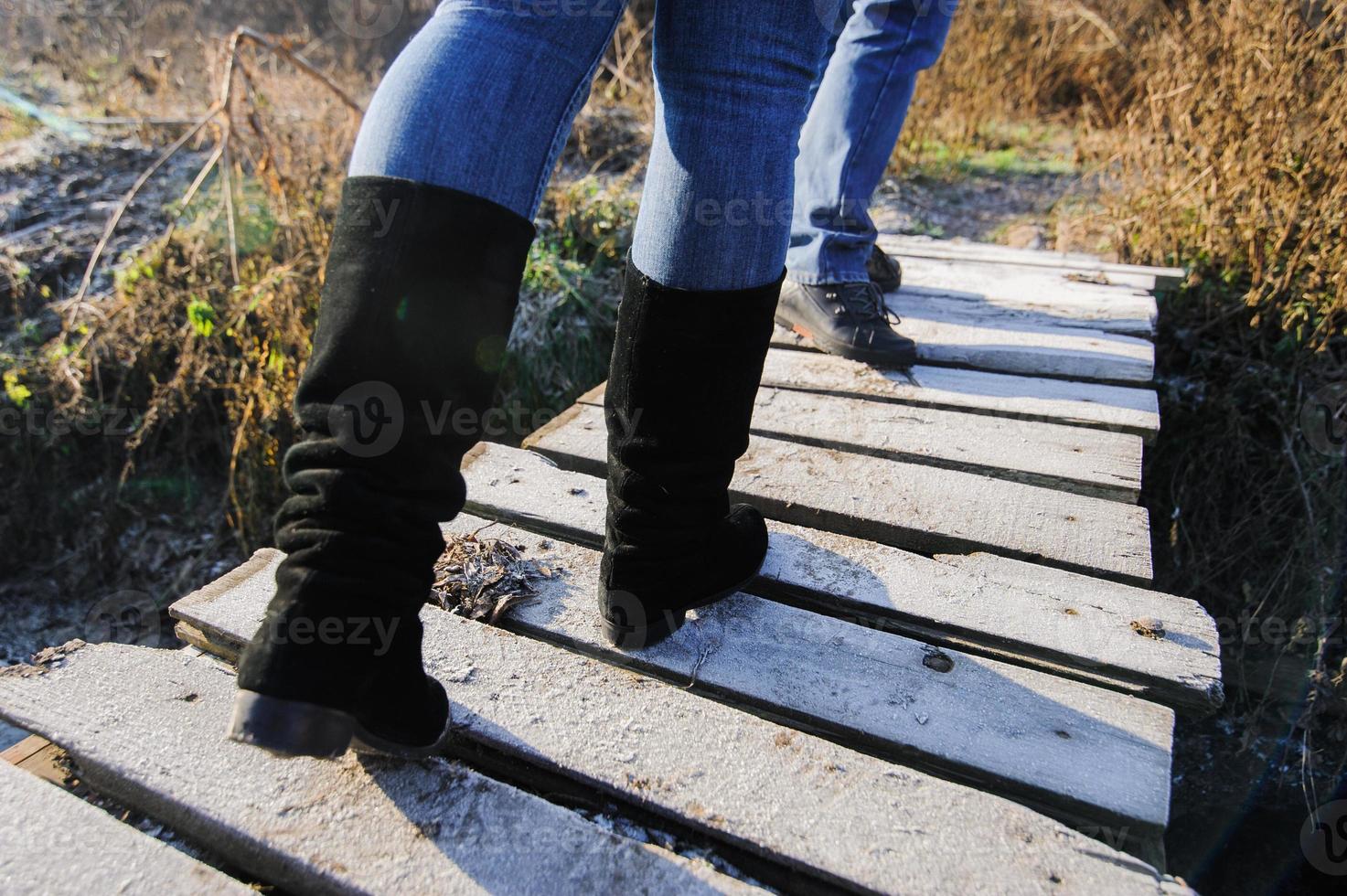 person in boots with jeans on the green grass near the snow spring is coming photo