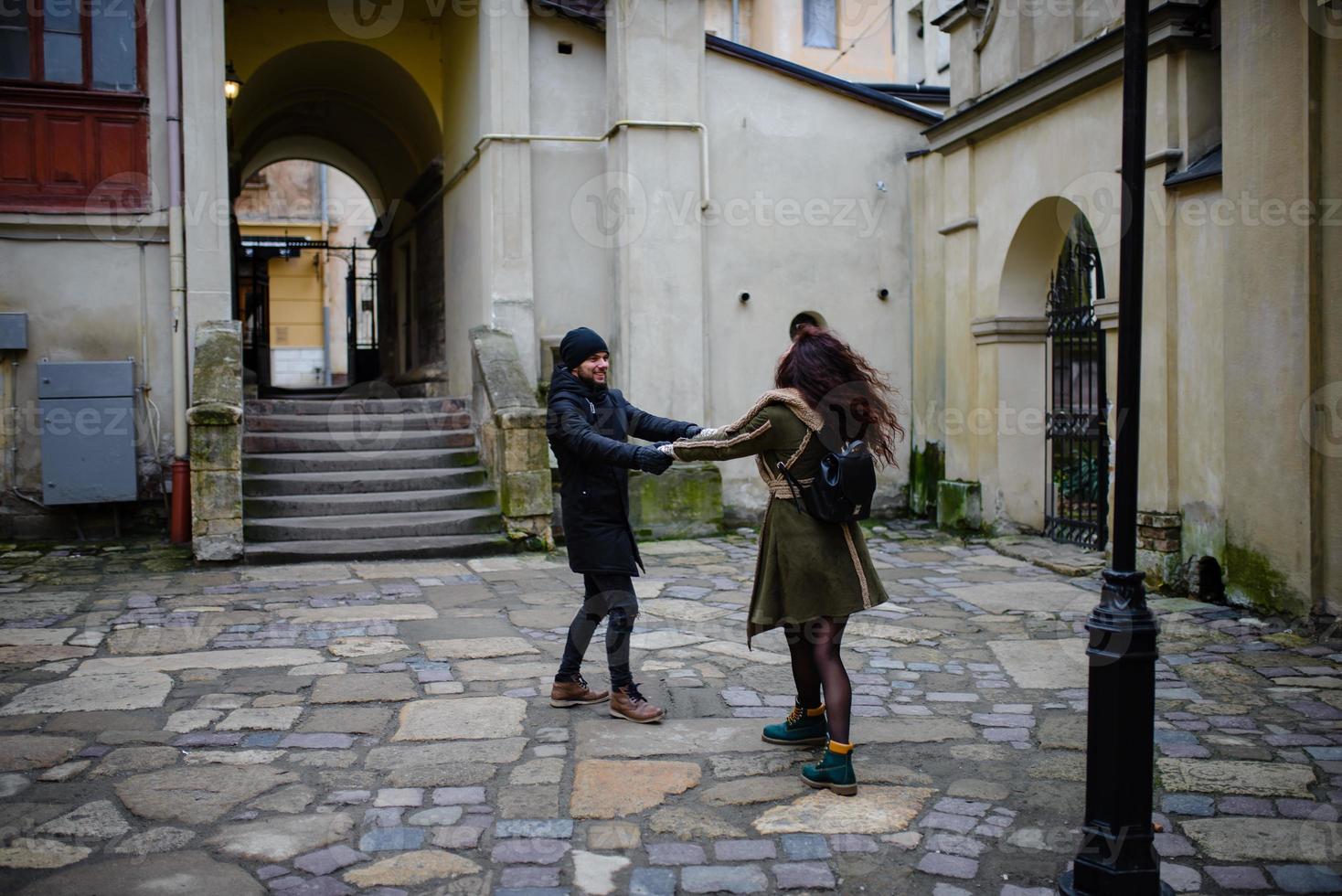 Loving couple having fun outdoors. Man covering eyes of woman with cap. photo