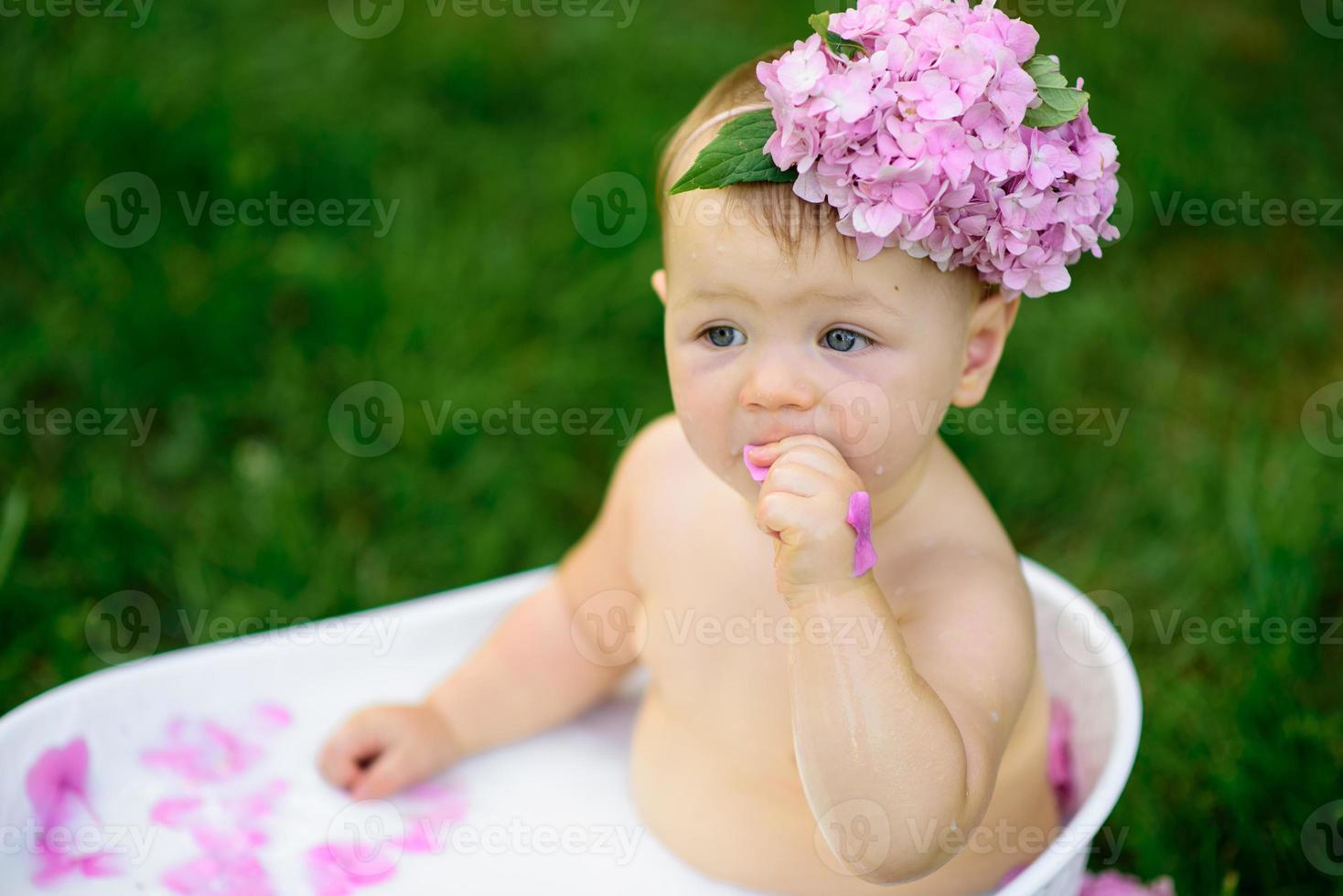 Little girl bathes in a milk bath in the park. The girl is having fun in the summer. photo