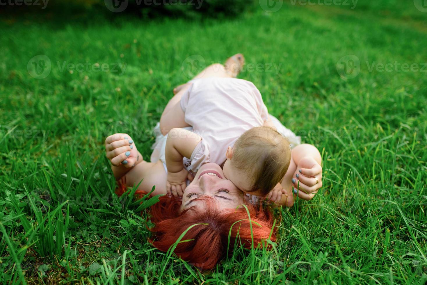 Mom hugs and plays with her one-year-old daughter wrapped in a towel after bathing. photo