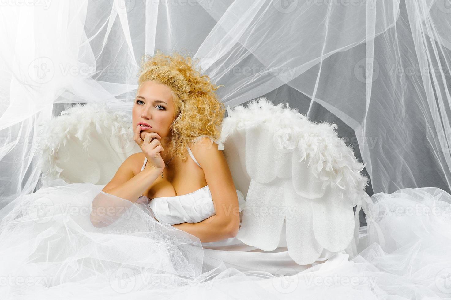 Sexy woman in angel costume posing in front of the camera. photo