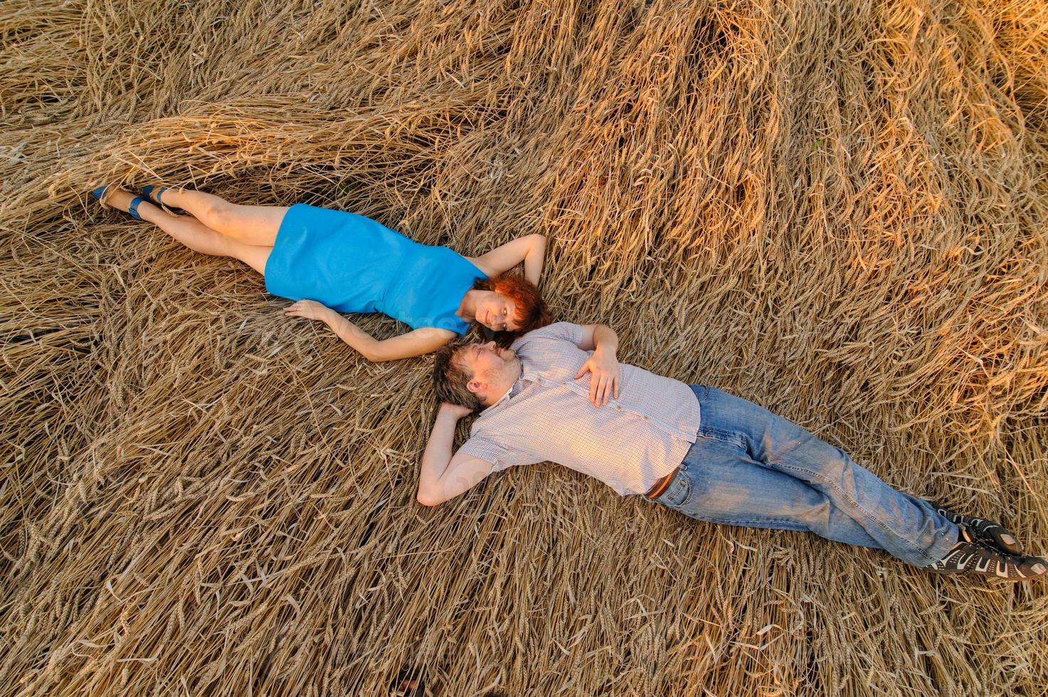 Adult farmer and wife spend time in the field. The man is sitting. A woman stands next to him and hugs him. A woman kisses her husband on the head. photo
