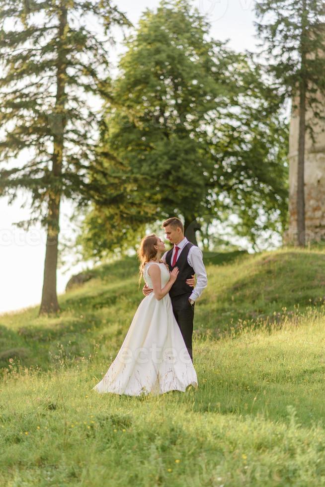 novia y novio en un campo de trigo. la pareja se abraza al atardecer foto