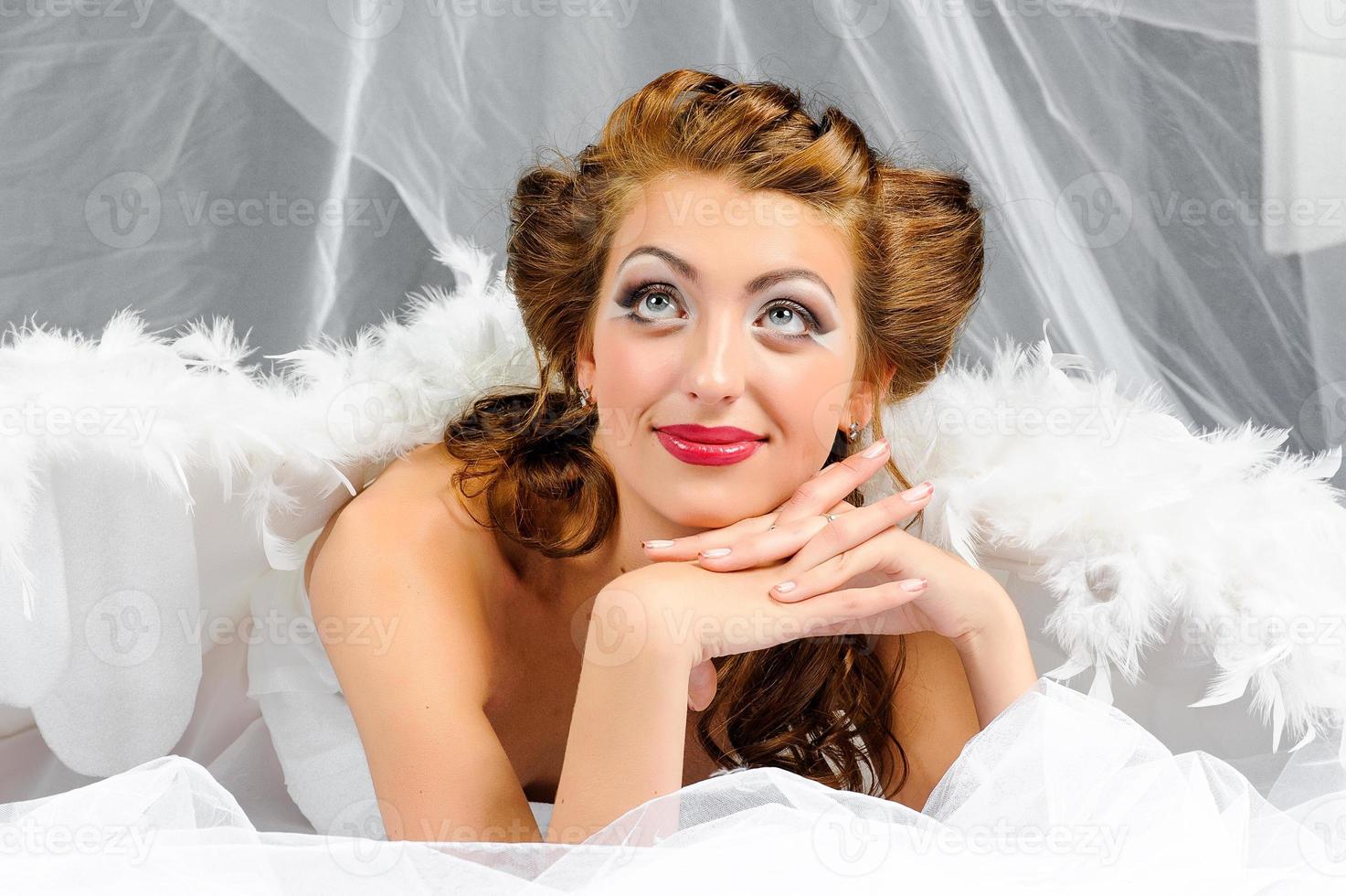 Sexy woman in angel costume posing in front of the camera. photo