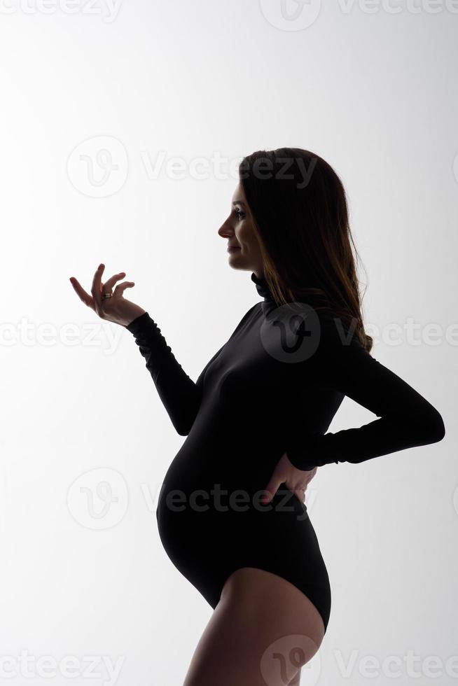 joven hermosa mujer embarazada en mono negro y sombrero. foto