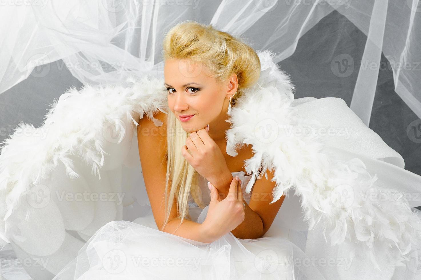 Sexy blonde woman in angel costume posing in front of the camera. photo