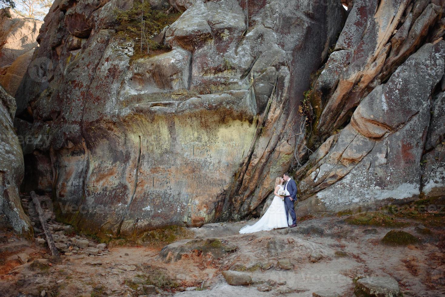 The bride and groom are standing on top of a cliff. Sunset. photo