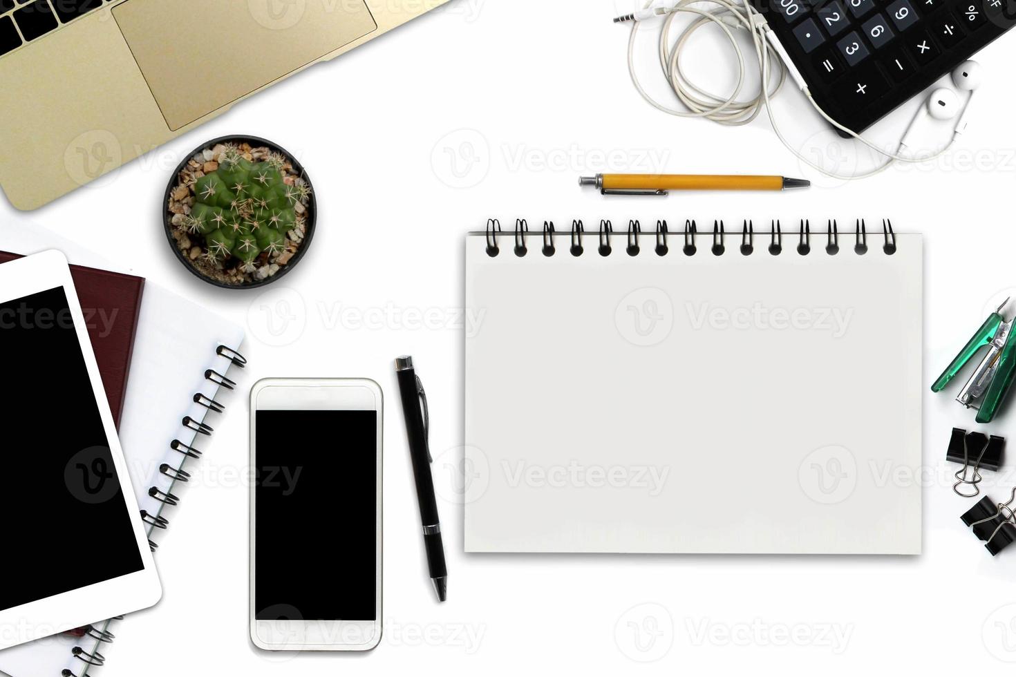 escritorio de oficina blanco con teléfono inteligente con pantalla negra, bolígrafo, computadora portátil, bloc de notas con espacio para copiar y suministros. vista superior con espacio de copia foto