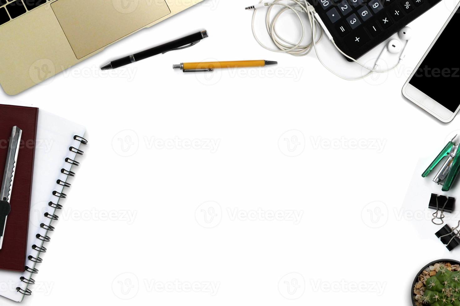 White office desk with smartphone with black screen, pen, laptop computer, notepad, and supplies. Top view with copy space photo