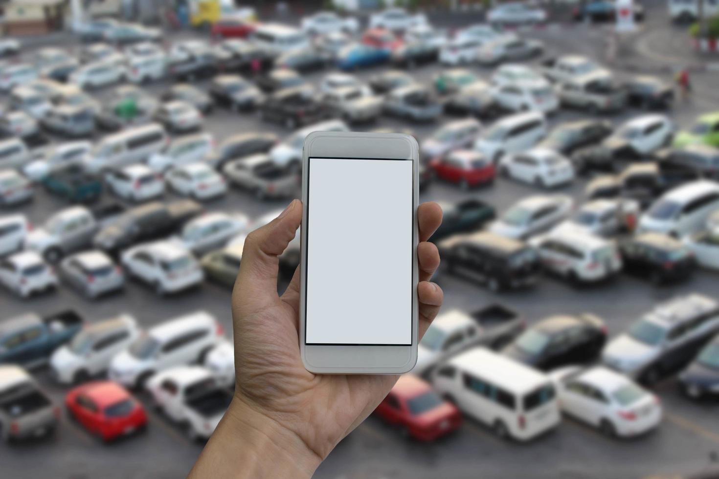 mano de hombre sosteniendo la pantalla vacía del teléfono inteligente y estacionamiento al aire libre foto