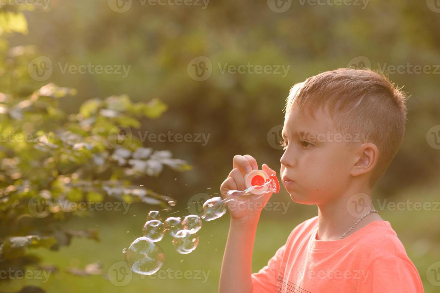 A boy of primary school age runs with balloons. The boy celebrates his birthday in the park. photo