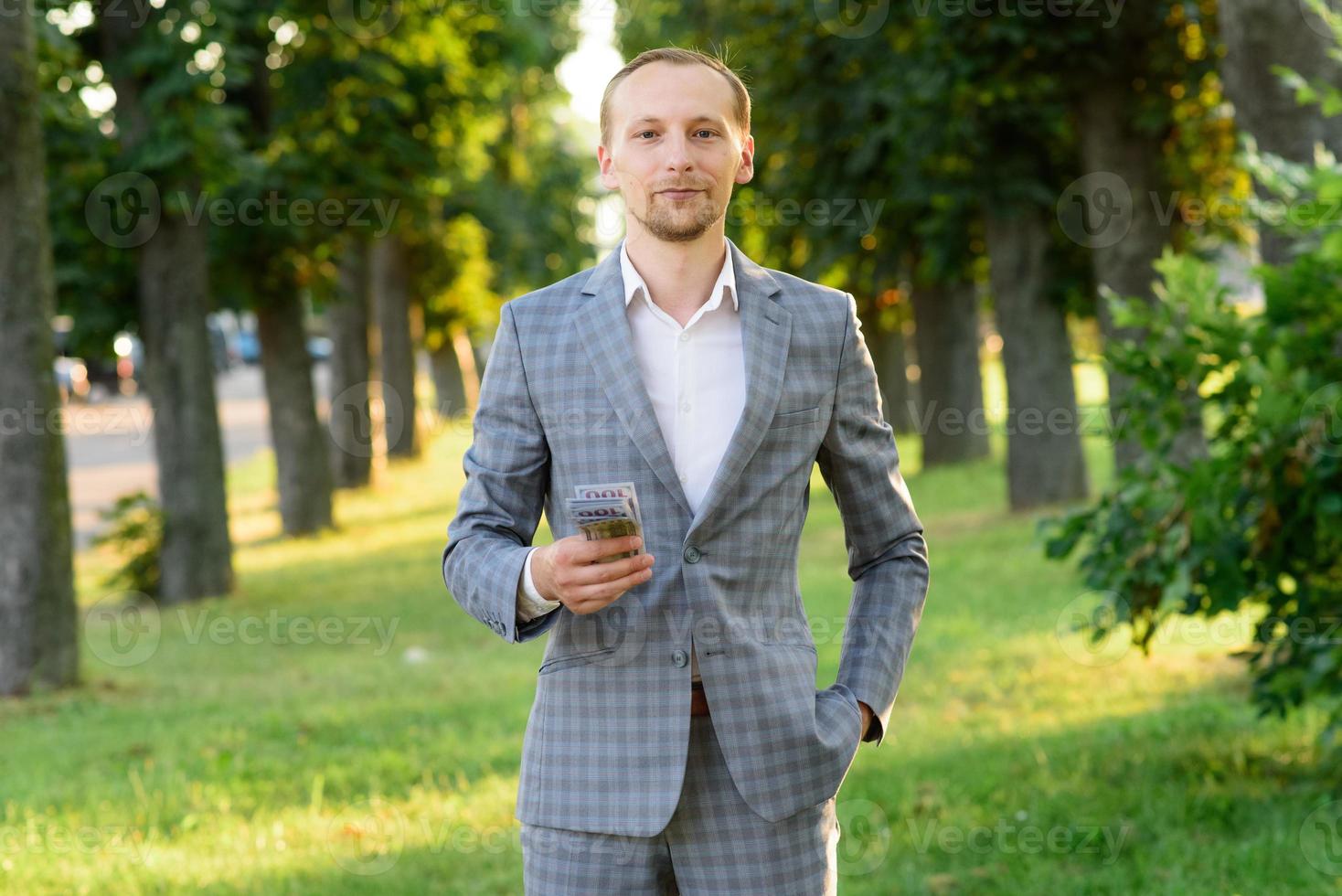 Young successful businessman shows money in his hand. photo