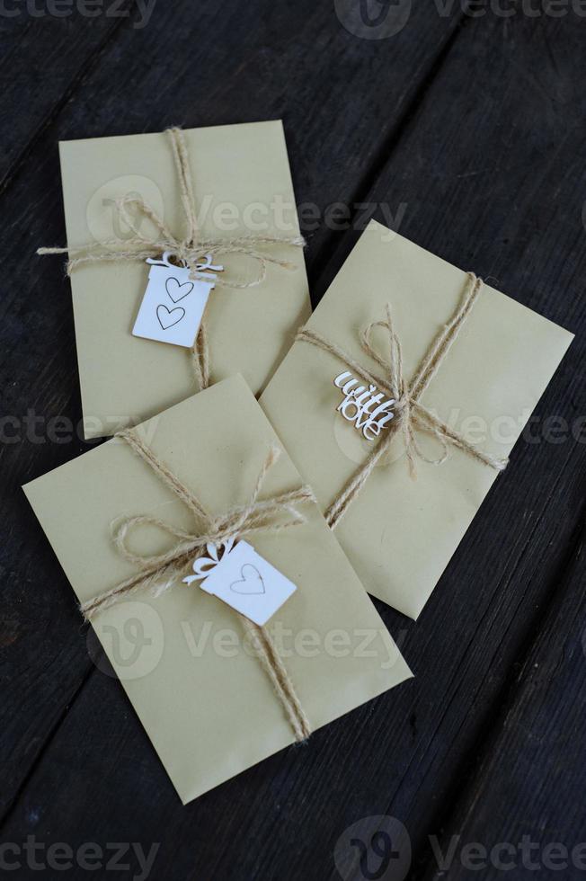 Brown kraft envelopes tied with an old tourniquet on old wood background with copy space. Handmade gift wrap. photo
