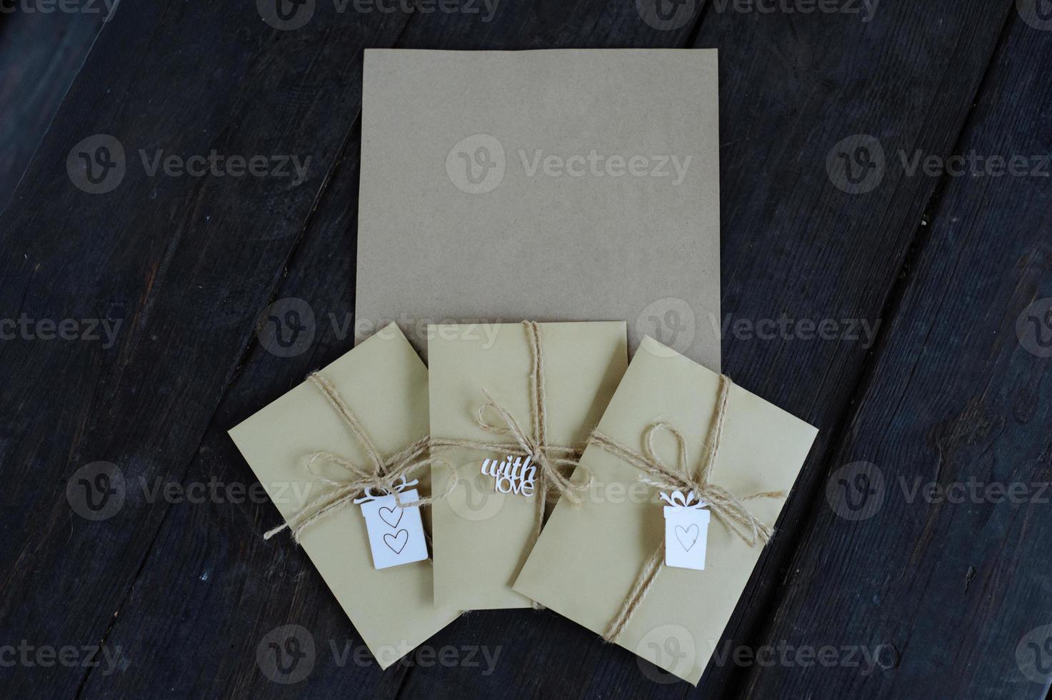 Brown kraft envelopes tied with an old tourniquet on old wood background with copy space. Handmade gift wrap. photo