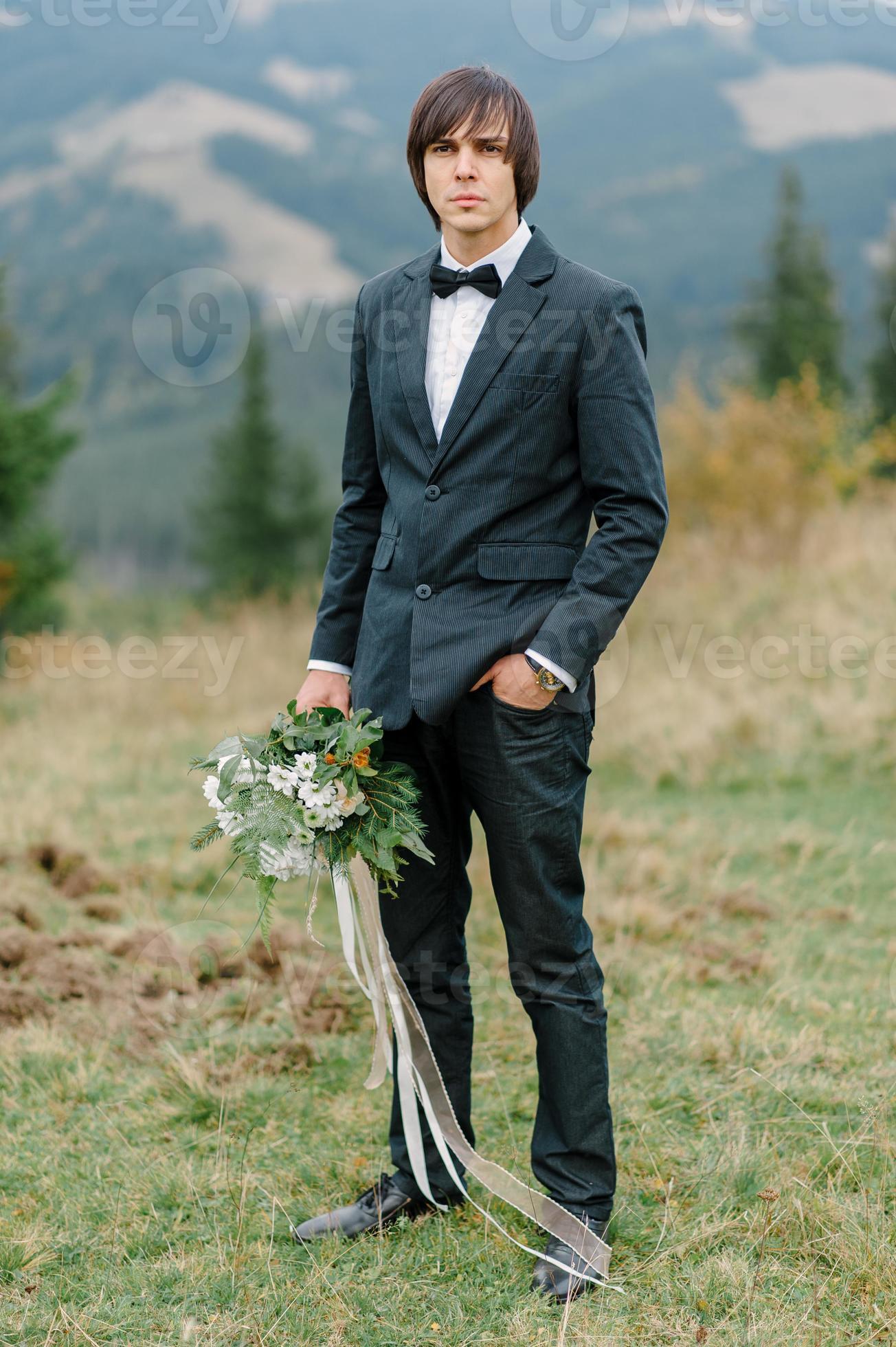 Handsome elegant bearded groom in checkered suit is standing on