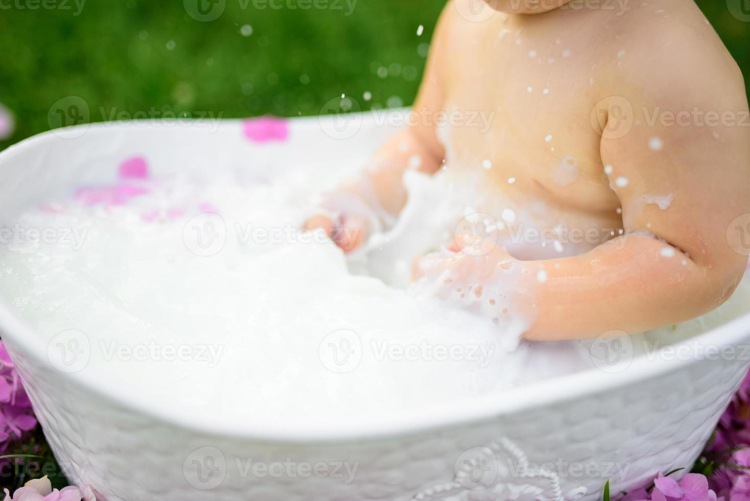 niña se baña en un baño de leche en el parque. la niña se está divirtiendo en el verano. foto