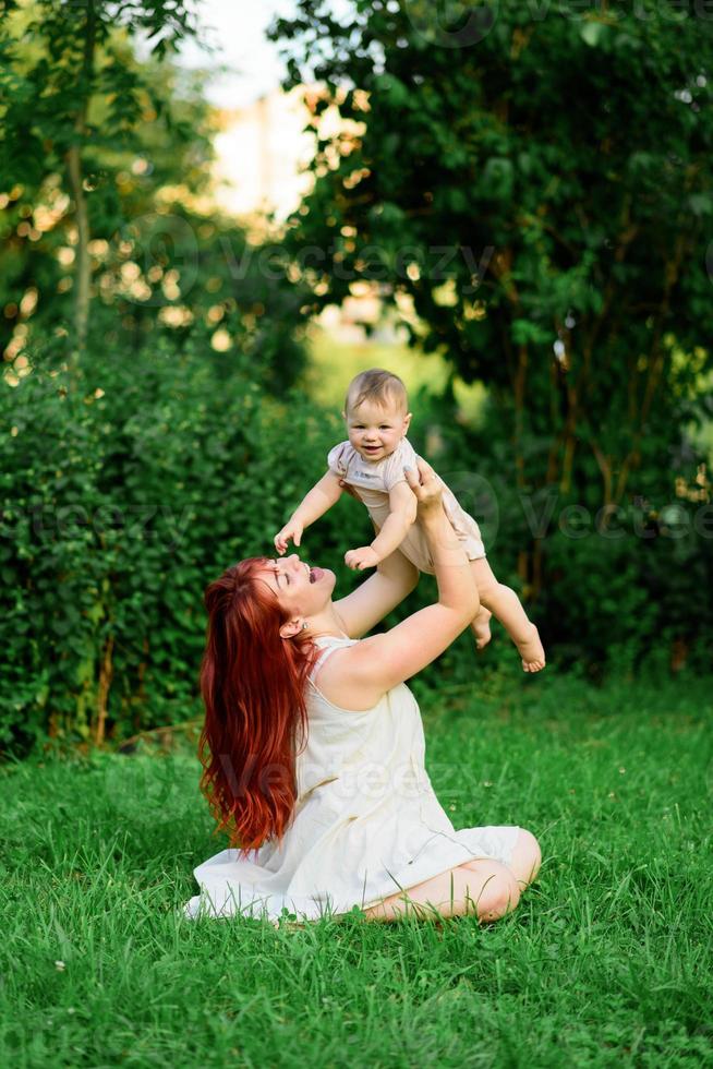 mamá abraza y juega con su hija de un año envuelta en una toalla después del baño. foto