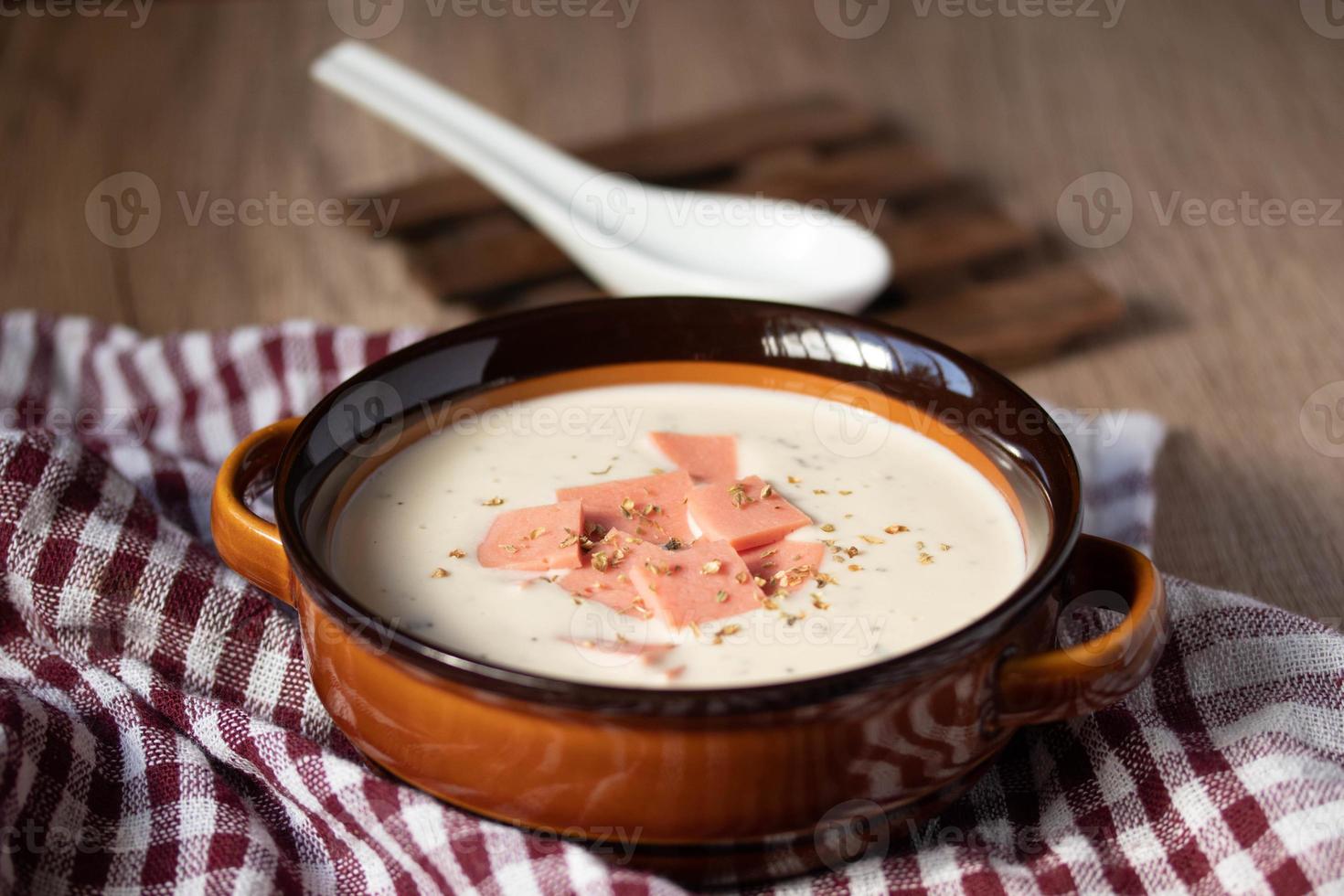 cheese soup with vegetables and ham with toast close-up on the table. horizontal sprinkle oregano in brown bowl. photo