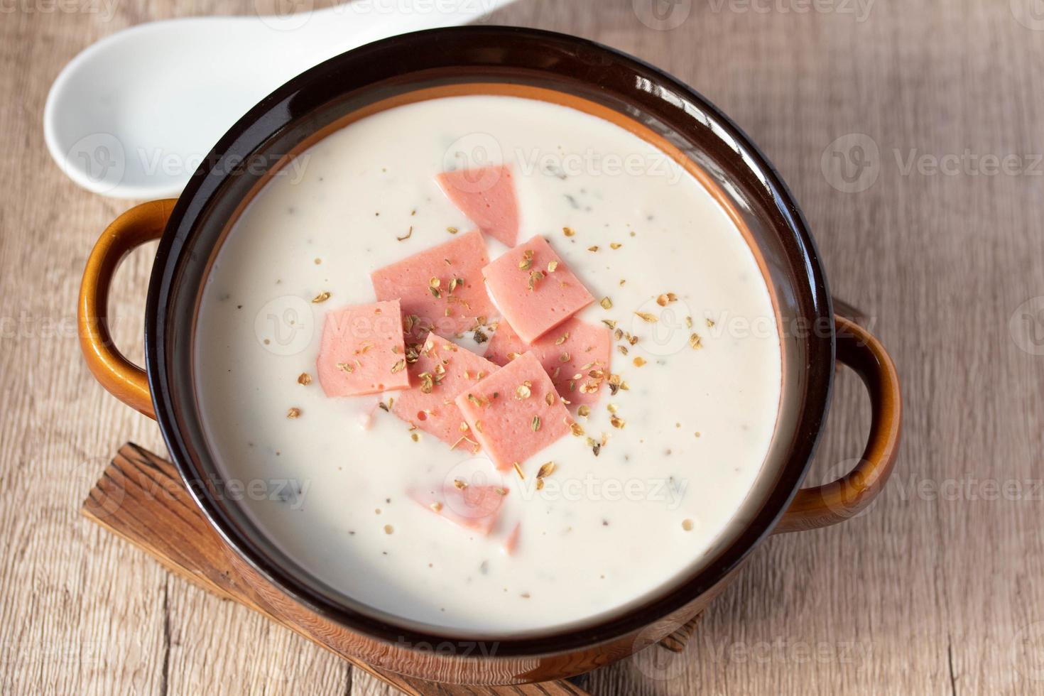 cheese soup with vegetables and ham with toast close-up on the table. horizontal sprinkle oregano in brown bowl. photo