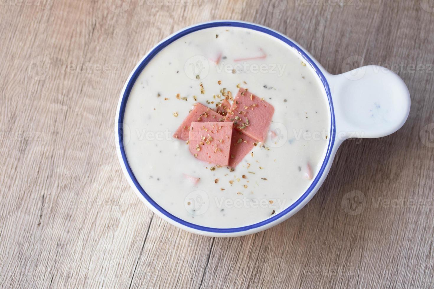 Cheese soup with vegetables and ham with toast on the table close-up horizontal sprinkle oregano in white bowl photo