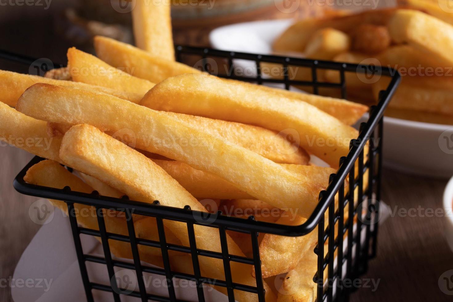 French fries in a black basket with tomato sauce photo
