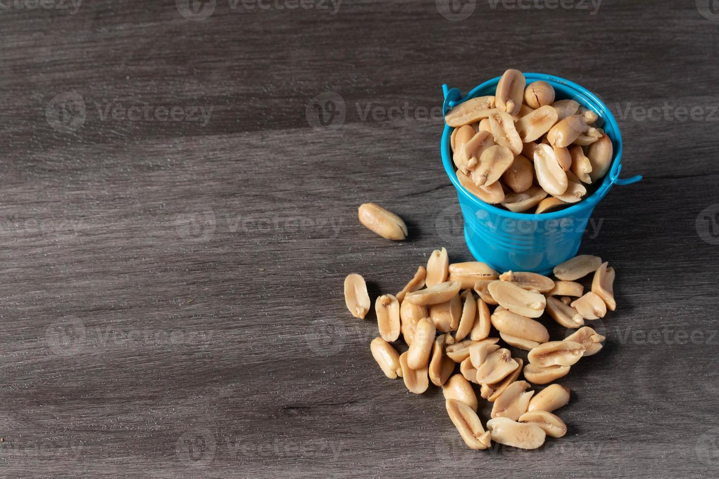 Baked peanuts in a bucket on a wooden background photo